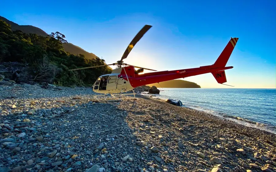 A helicopter landed on the stony beach at the mouth of the fiord