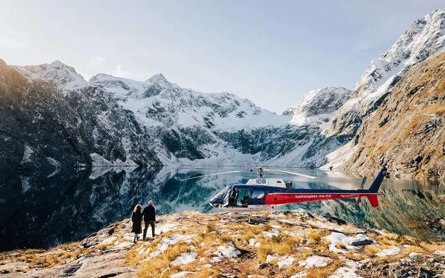 A helicopter landed on an alpine ridge above the fiord